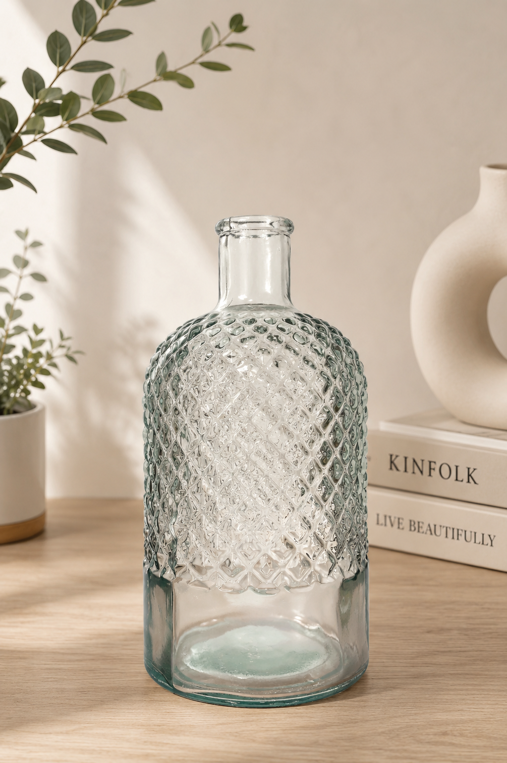 Diamond cut glass bottle vase styled with eucalyptus and Kinfolk books on a wooden surface