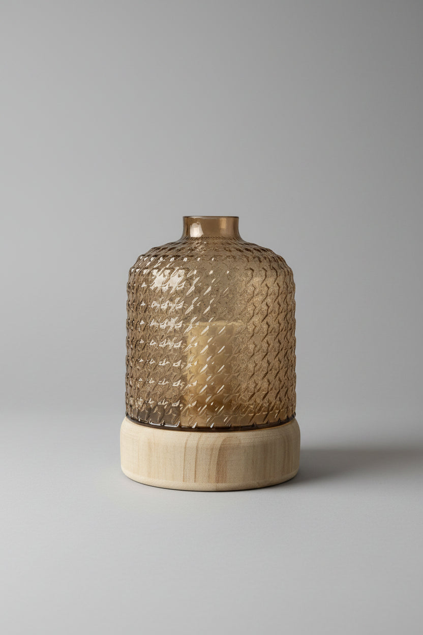 Smoked amber textured glass vase with ribbed wooden base on a wooden surface