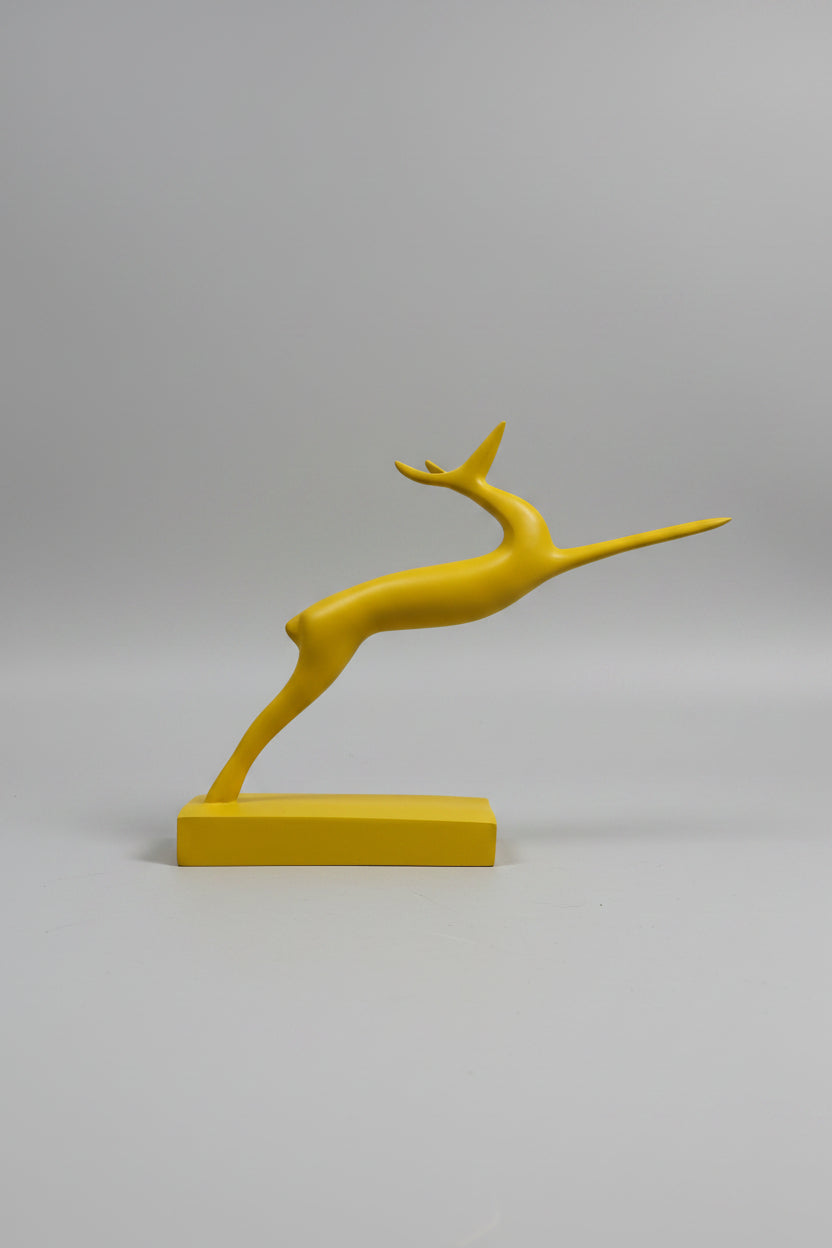 Abstract leaping gazelle sculpture in mustard yellow matte finish on matching base